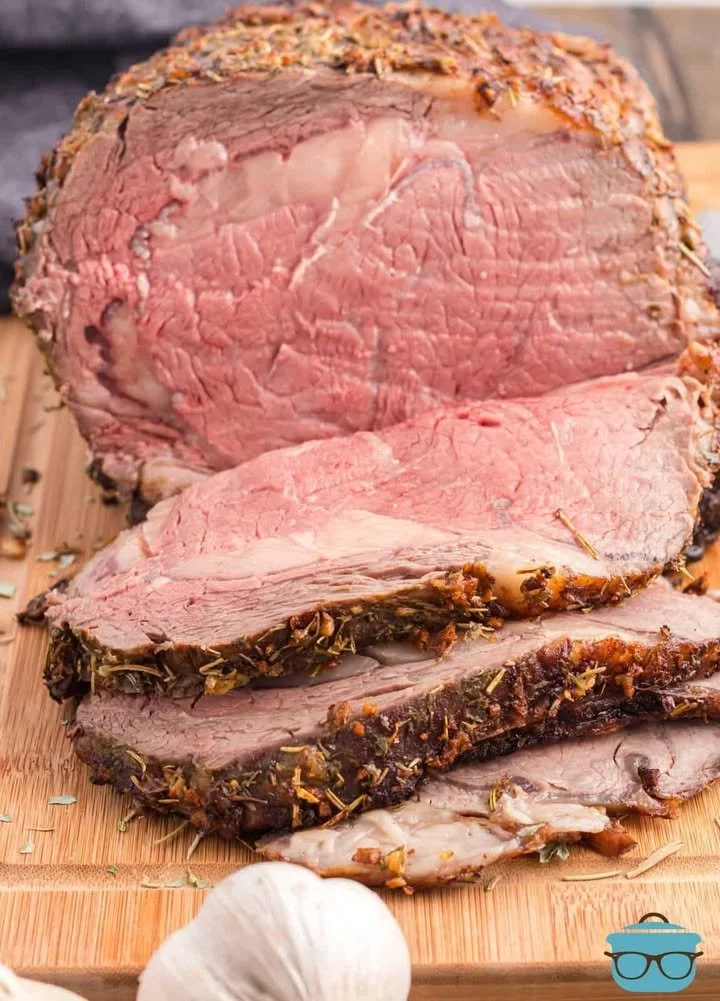 A succulent garlic butter prime rib roast served with herbs and sides.